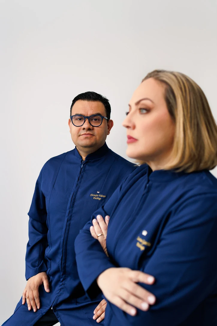 Christofer e Luciane de jaleco azul-marinho, em um retrato com fundo claro