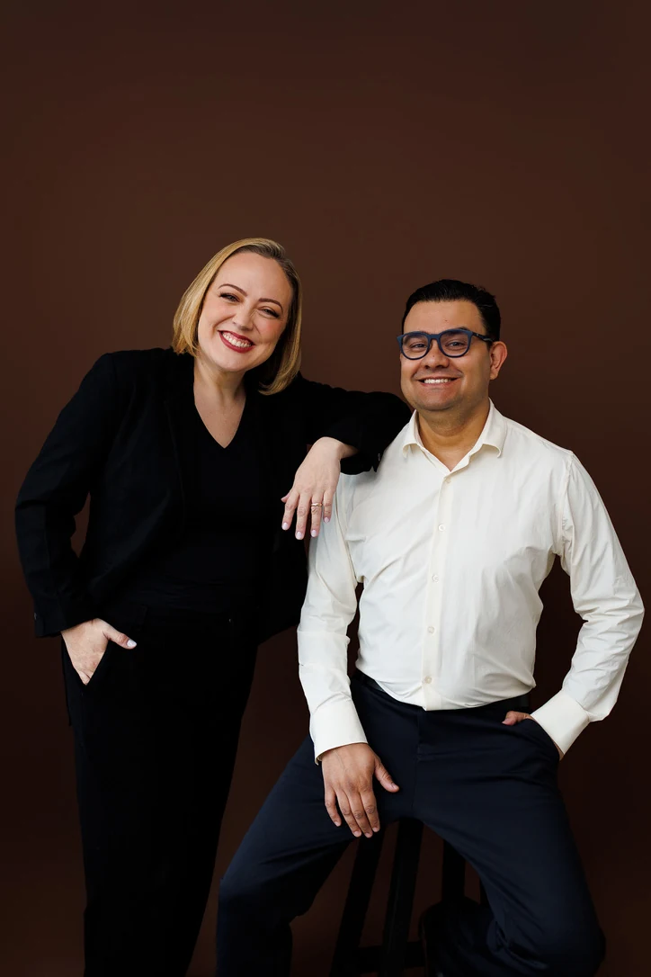 Luciane e Christofer posando lado a lado diante de um fundo marrom