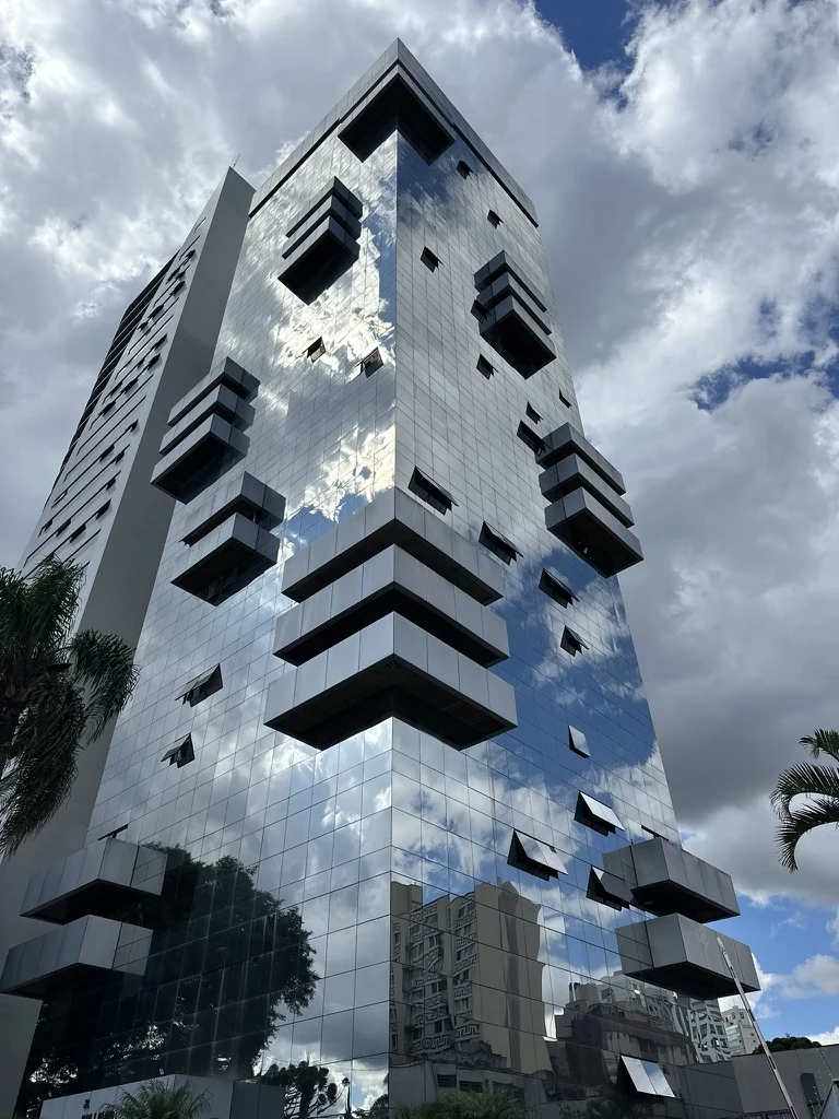 Edifício de fachada espelhada refletindo o céu, onde fica a clínica na Avenida Cândido de Abreu